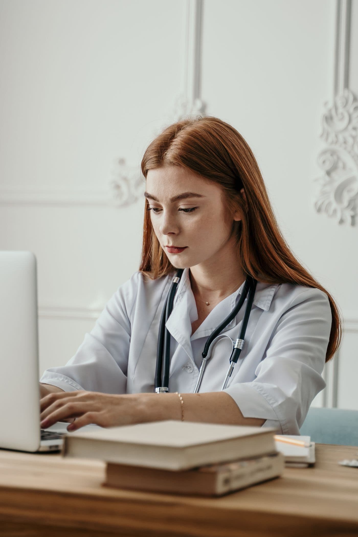 Dokter perempuan menggunakan software klinik Medhop melalui laptop
